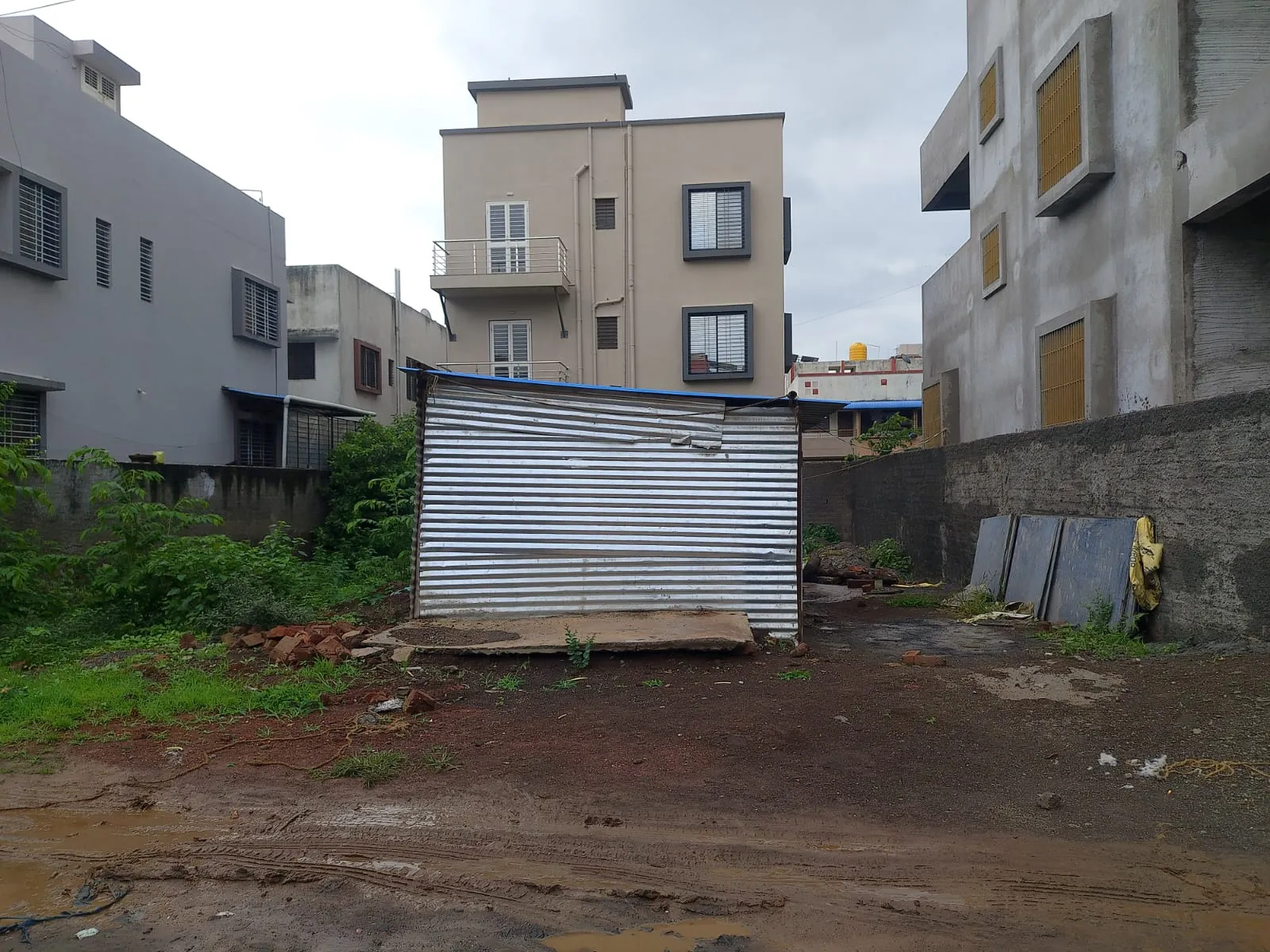 The vacant residential plot at Gut No. 551, Adgaon, bordered by neighbouring homes