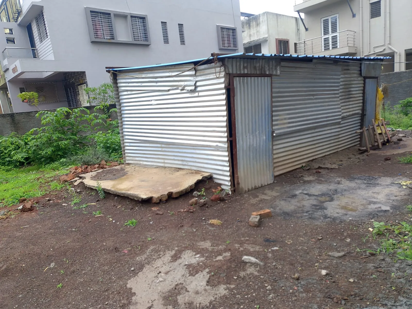 On-site view of the Adgaon plot boundary with neighbouring bungalows behind